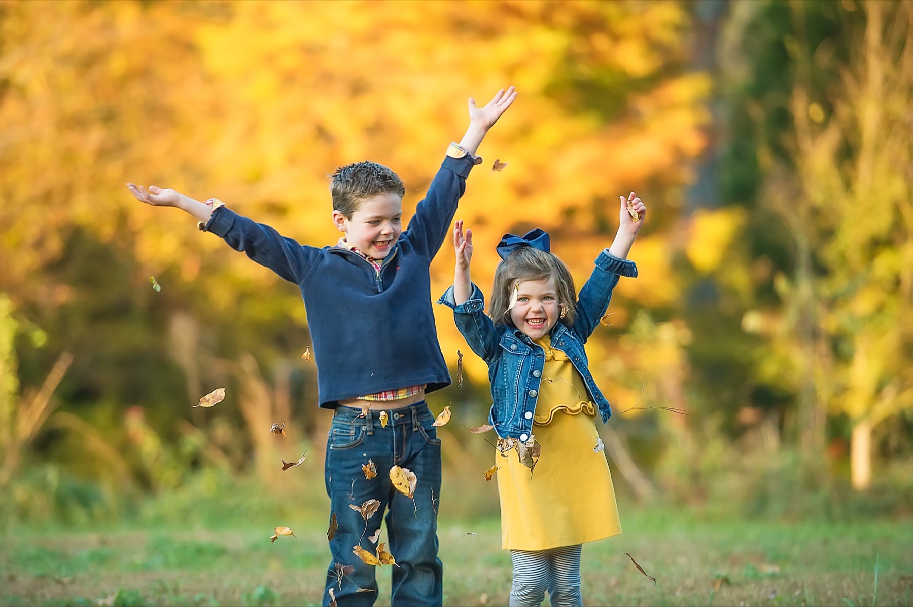 Two children playing in autumn leaves