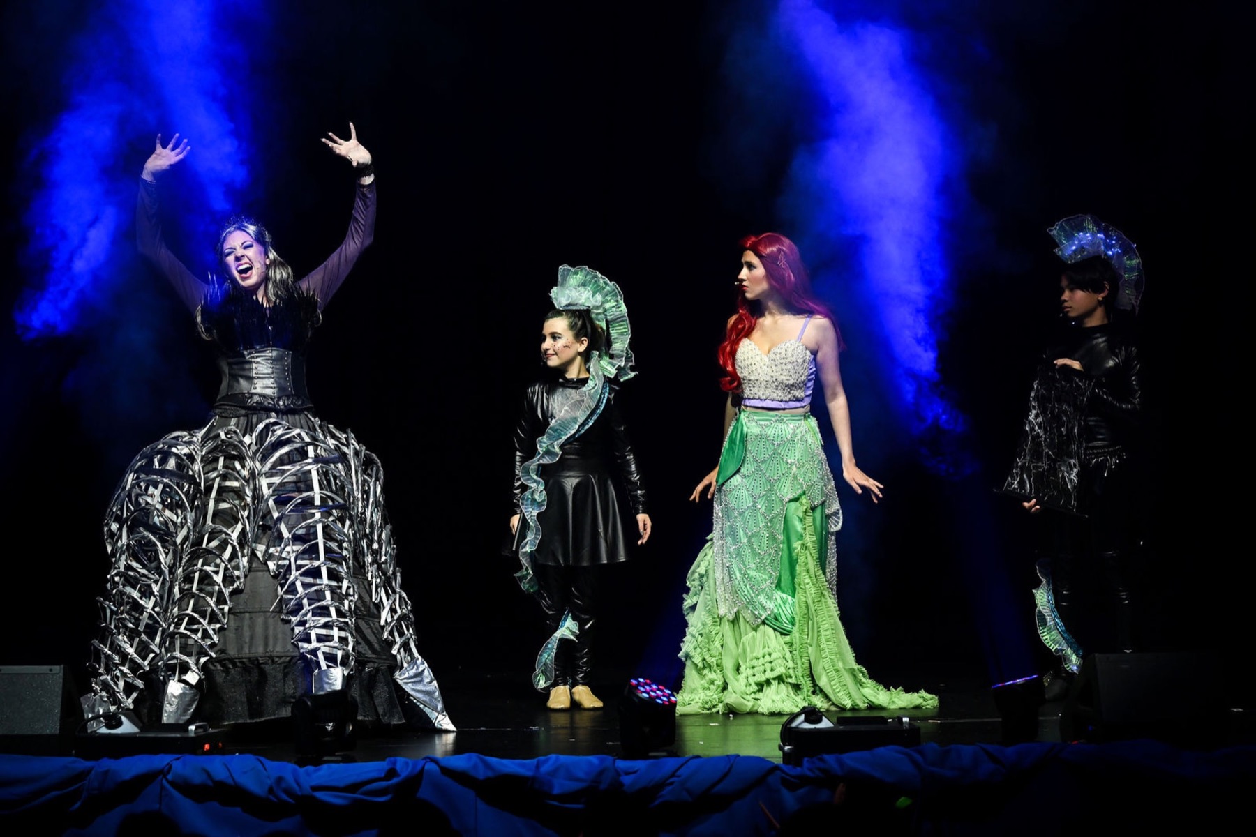 Performers under dramatic blue stage lighting